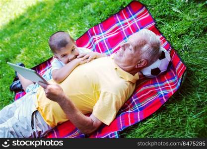 grandfather and child using tablet computer in park. grandfather and child in park using tablet