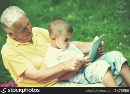 grandfather and child using tablet computer in park. grandfather and child in park using tablet