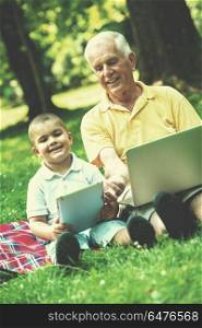 grandfather and child using tablet computer in park. grandfather and child in park using tablet