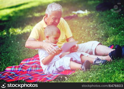 grandfather and child using tablet computer in park. grandfather and child in park using tablet