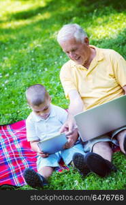 grandfather and child using tablet computer in park. grandfather and child in park using tablet