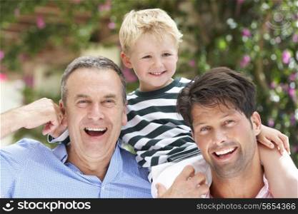 Grandfather And Father Giving Grandson Ride On Shoulders