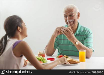 Grandfather and granddaughter eating breakfast