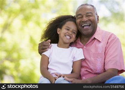 Grandfather and granddaughter outdoors smiling
