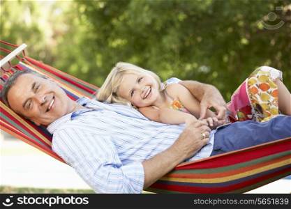 Grandfather And Granddaughter Relaxing In Hammock