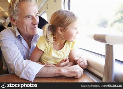 Grandfather And Granddaughter Relaxing On Train Journey