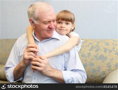 grandfather and granddaughter sitting on the sofa and hugging