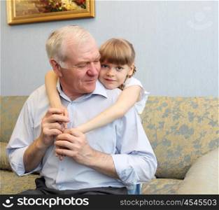 grandfather and granddaughter sitting on the sofa and hugging