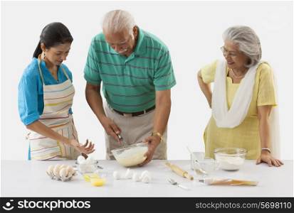 Grandfather and granddaughter working in the kitchen while grandmother looks on