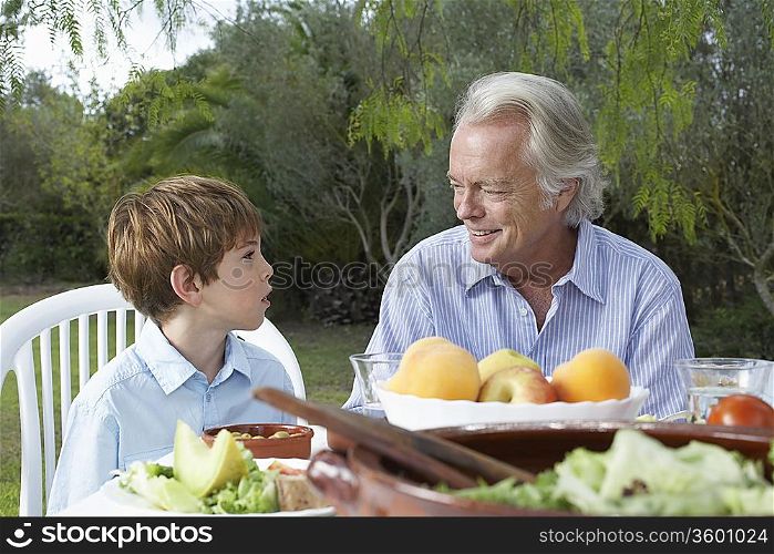 Grandfather and grandson (5-6) at garden table
