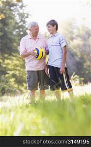 Grandfather and grandson at a park holding a ball and smiling