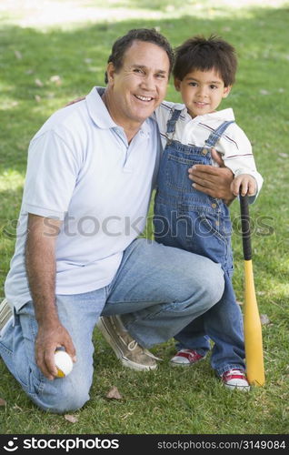 Grandfather and grandson holding baseball bat and smiling