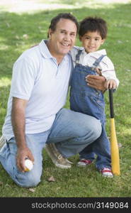 Grandfather and grandson holding baseball bat and smiling