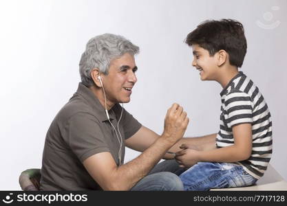 Grandfather and grandson listening to music with earphones 