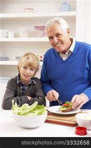 Grandfather And Grandson Making Sandwich In Kitchen