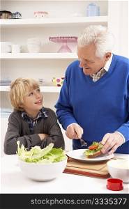 Grandfather And Grandson Making Sandwich In Kitchen