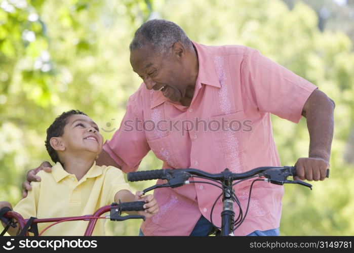 Grandfather and grandson on bikes outdoors smiling