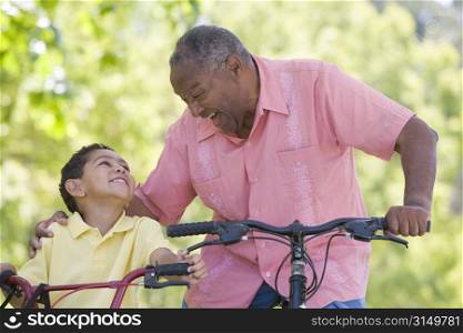 Grandfather and grandson on bikes outdoors smiling