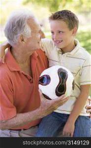 Grandfather and grandson outdoors with ball smiling