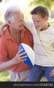Grandfather and grandson outdoors with football smiling