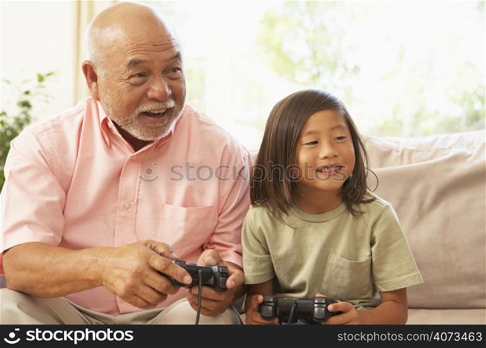 Grandfather And Grandson Playing Computer Game At Home