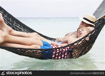 Grandfather And Grandson Relaxing In Beach Hammock