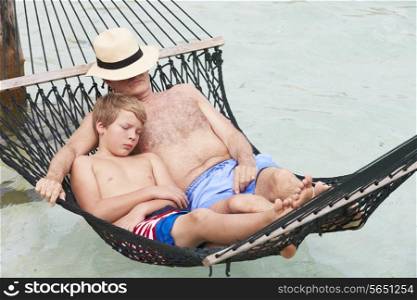 Grandfather And Grandson Relaxing In Beach Hammock