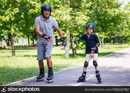 Grandfather and grandson roller skating in the park