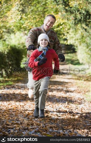 Grandfather and grandson running outdoors in park and smiling