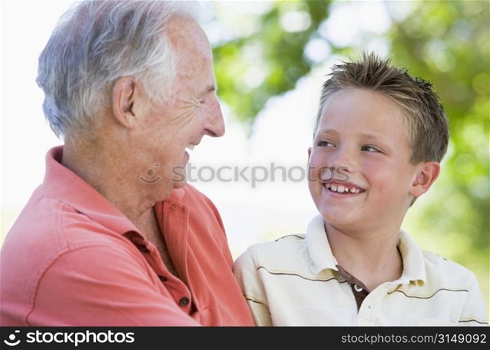 Grandfather and grandson smiling outdoors.