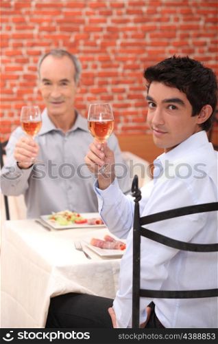 Grandfather and grandson toasting with wine