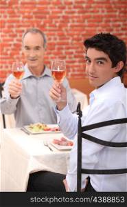 Grandfather and grandson toasting with wine