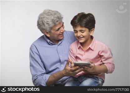 Grandfather and grandson using digital tablet 