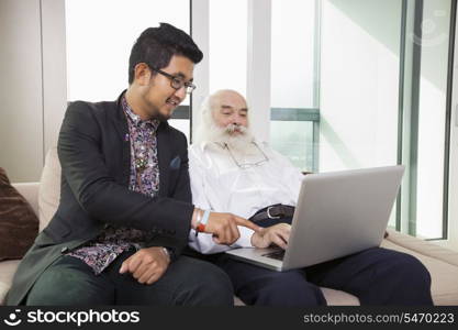 Grandfather and grandson using laptop in living room