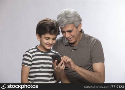Grandfather and grandson using mobile phone