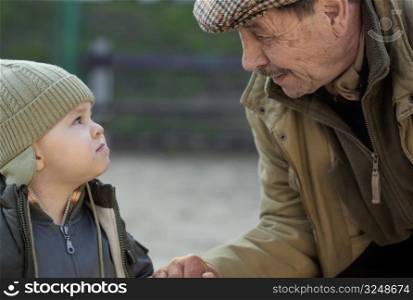 Grandfather and his 2 years old grandson looking at each other.