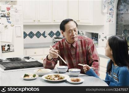 Grandfather and his granddaughter sitting at a table