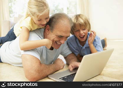 Grandfather AndGrandchildren Using Laptop At Home