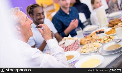 grandfather eating dates with modern multiethnic muslim family while enjoying iftar dinner together during a ramadan feast at home