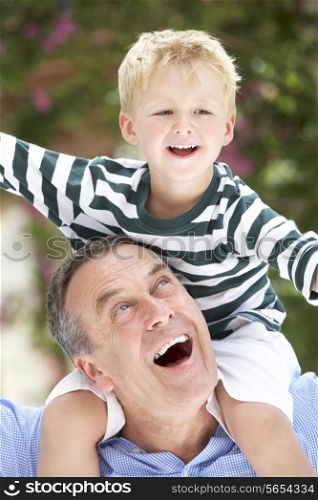 Grandfather Giving Grandson Ride On Shoulders Outdoors