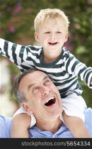 Grandfather Giving Grandson Ride On Shoulders Outdoors