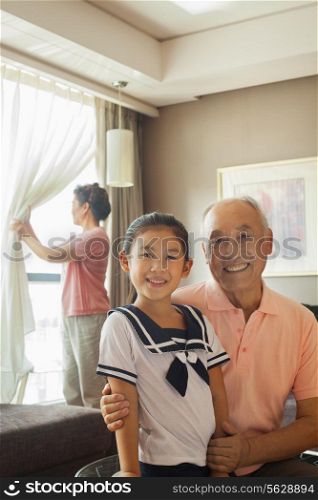 Grandfather holding her granddaughter, grandmother in the background