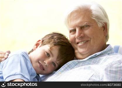 Grandfather Hugging Grandson In Park