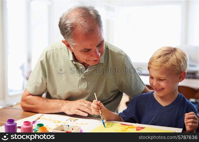 Grandfather Painting Picture With Grandson At Home