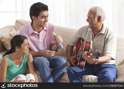 Grandfather playing the guitar and grandchildren singing