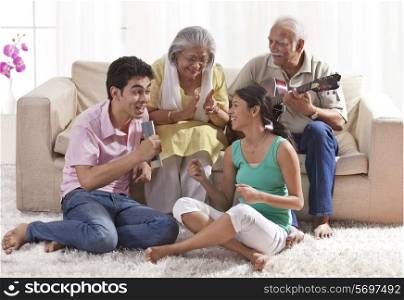 Grandfather playing the guitar with grandmother and grandchildren singing