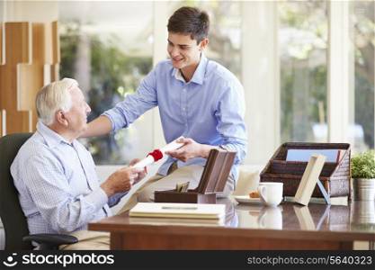 Grandfather Showing Document To Teenage Grandson