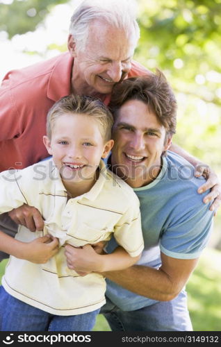 Grandfather with adult son and grandchild in park