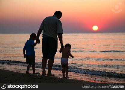 Grandfather with children on sunset at sea