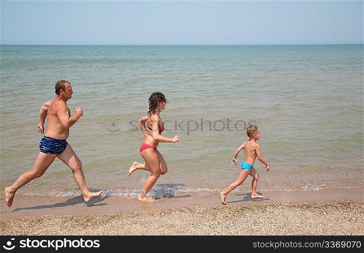 Grandfather with daughter and grandson run as to beach
